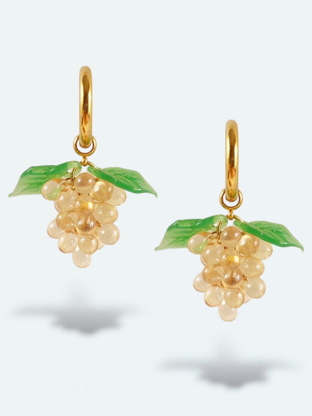 Handmade gold hoop earrings with grape charm made of beige glass drops.